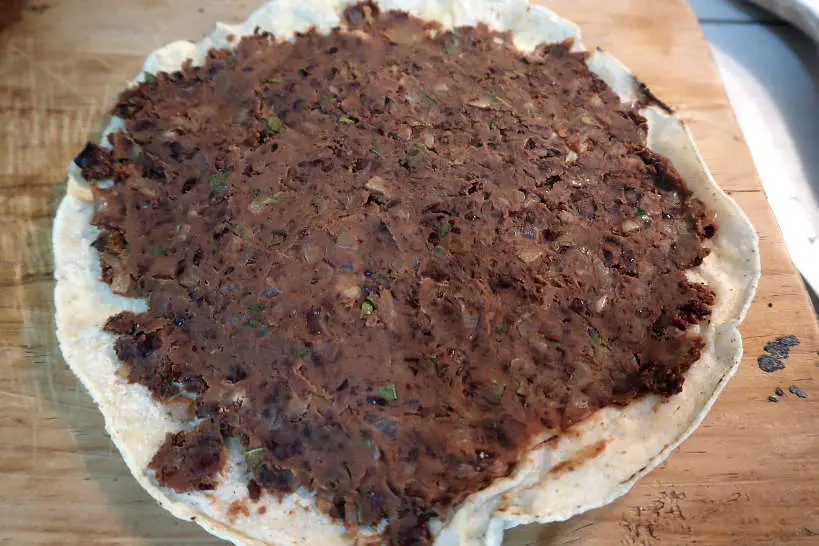 Refried beans on tortilla for tlayuda recipe by Authentic Food Quest